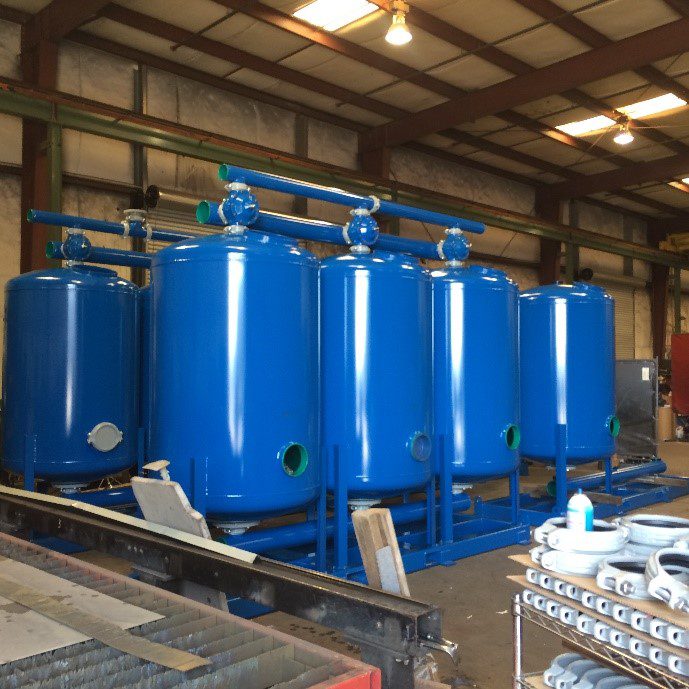 A group of blue tanks in a warehouse.