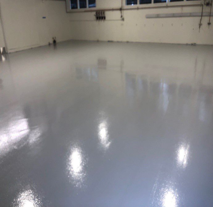 A well polished floor in white with lights reflecting of a warehouse