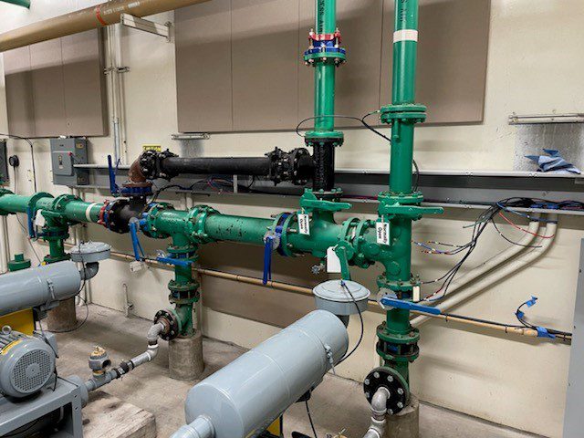 A view inside of a factory with green metal pipelining and connecting with each other