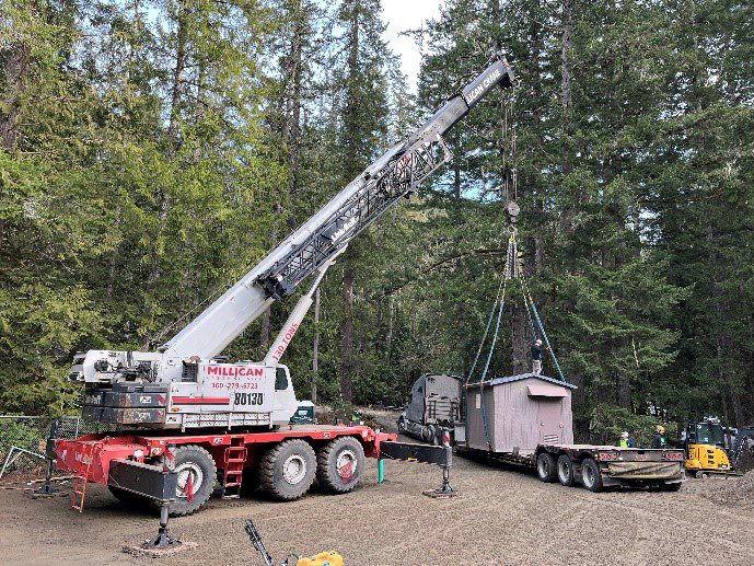 A crane is being used to move a large piece of wood.